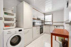 eine weiße Küche mit einer Waschmaschine und einem Tisch in der Unterkunft Apartamento WELCS PDA -114- en el puerto con piscina in Platja  d'Aro