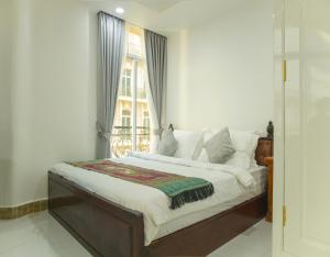 a bedroom with a large bed with a window at Try Residence, The Elysée Koh Pich in Phnom Penh