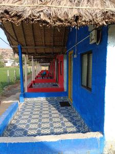um prédio azul e vermelho com piso de ladrilho em Laughing Buddha hampi guest House em New Hampi