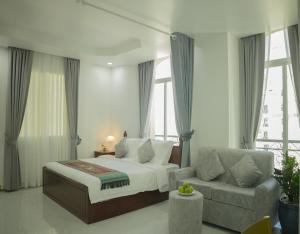 a bedroom with a bed and a couch and windows at Try Residence, The Elysée Koh Pich in Phnom Penh