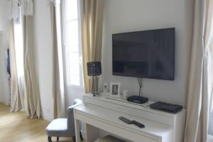 uma sala de estar com televisão numa parede branca em LE REGRATTIER ST LOUIS em Paris