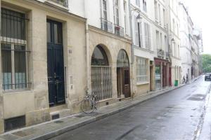 uma bicicleta estacionada ao lado de um edifício numa rua em LE REGRATTIER ST LOUIS em Paris