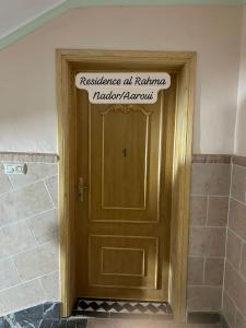 a wooden door with a sign on top of it at Residence al Rahma nr 01 in Monte ʼArrouit