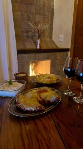 una mesa con copas de vino y comida y una chimenea en Chalé Sorrizão- Visconde de Mauá, en Bocaina de Minas