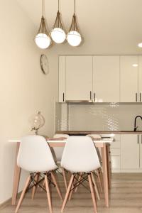 eine Küche mit einem Tisch und 2 weißen Stühlen in der Unterkunft Apartman Biser 4 in Ruma