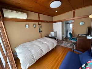 Schlafzimmer mit einem weißen Bett und einem Schreibtisch in der Unterkunft Sakura house in Kyoto