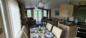 een keuken en een woonkamer met een tafel in een caravan bij Golden Anchor Caravan Park, Europa Sequoia Private Static Caravan Hire on Wildflower Meadow in Chapel Saint Leonards