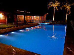 - une grande piscine bleue ouverte la nuit avec des palmiers dans l'établissement Sitio Pedacinho do Céu, à Bragança Paulista