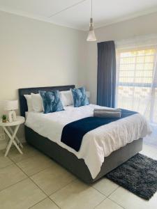 a bedroom with a large bed with blue pillows at Joy Apartment@The Blyde in Pretoria