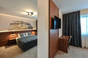 a hotel room with a bed and a television at Tvrdjava Rooms in Novi Sad