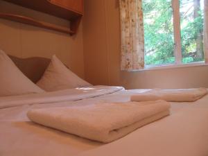 zwei Handtücher liegen auf einem weißen Bett mit Fenster in der Unterkunft Mobile Home Gorecki in Lidzbark Warmiński