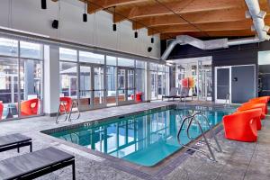 una piscina en un edificio con sillas rojas en Aloft Nashville Franklin en Franklin