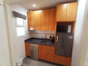 kuchnia z drewnianymi szafkami i zlewem w obiekcie Appartement Torremolinos Dona Carlota w mieście Torremolinos