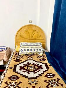 een bed met een houten hoofdeinde met een tapijt erop bij Calm 2BR Home with Garden in New Cairo in Caïro