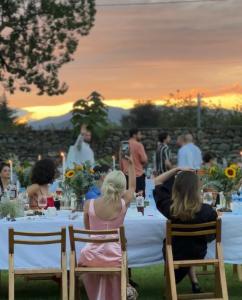 een groep mensen die bij zonsondergang aan een tafel zitten bij Chubini Winery & Cabins in Kvareli