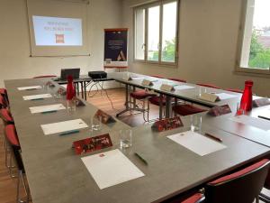 une salle de réunion avec une grande table et des chaises rouges dans l'établissement Ibis Brive Centre, à Brive-la-Gaillarde