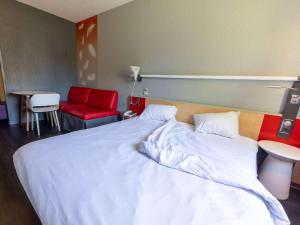 1 dormitorio con 1 cama blanca grande y sillas rojas en ibis Vesoul, en Vesoul