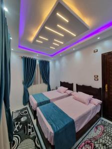 two beds in a room with purple lighting at Happy pyramids inn Hotel in Cairo