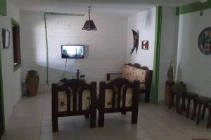 Zimmer mit Stühlen und einem TV an der Wand in der Unterkunft Chalé Pé na Areia, Cond. Beira Mar, Maragogí/AL in Maragogi