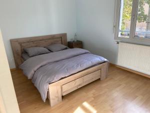 un letto con struttura in legno in una camera da letto di 2BHK Entire Apartment fully equipped 84m2 a Lione