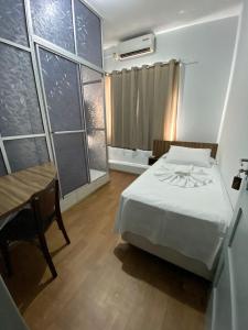 a bedroom with a bed and a table and a tub at Hotel Ferrari in Rio do Sul