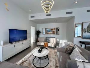 a living room with a couch and a flat screen tv at 1BR Americana Apartment: Stars and Stripes Haven in Abu Dhabi
