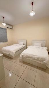 two beds with white sheets in a room at Chic 3-BR Tala Almajd Villas in upscale district Alnahdah Family only in Jeddah