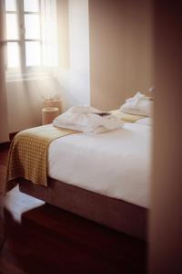 Un dormitorio con una cama blanca con una manta. en Casa do Gadanha, en Estremoz
