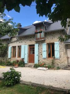 ein Steinhaus mit blauen Türen und einem Balkon in der Unterkunft The Chamberet Grand Coeur in Chamberet