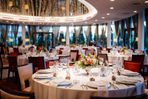 een eetkamer met witte tafels en stoelen met bloemen bij Ramada Plaza Craiova in Craiova