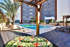 um pátio com uma mesa e uma piscina em Wyndham Golden Foz Suítes em Foz do Iguaçu