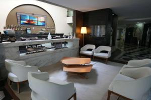 a lobby with a bar with white chairs and a table at Wyndham Golden Foz Suítes in Foz do Iguaçu