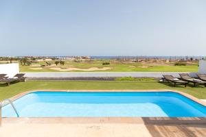 a swimming pool with a view of a golf course at Ereza White Homes in Caleta De Fuste