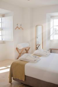 Habitación blanca con 2 camas y espejo. en Casa do Gadanha en Estremoz