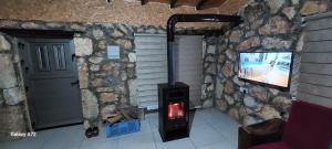 a wood stove in a room with a tv at Borak's Stone Village in Rizokarpaso +10 photos