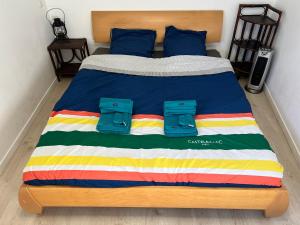een bed met een kleurrijk gestreept dekbed en 2 paar slippers bij Studio indépendant plein pied avec mezzanine in Joinville-le-Pont
