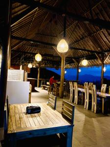 restauracja z drewnianym stołem, krzesłami i światłami w obiekcie Ara Artati Lombok bungalows and Restaurant w mieście Selong Belanak