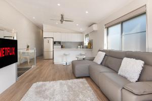 a living room with a couch and a kitchen at Modern & Convenient Apartment in Maroochydore