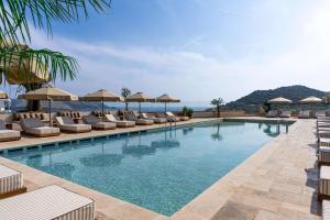 a swimming pool with lounge chairs and umbrellas at Radisson Blu Hotel, Kas in Kaş