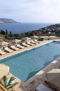 a swimming pool with lounge chairs and the ocean at Radisson Blu Hotel, Kas in Kaş