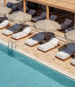 a pool with lounge chairs and umbrellas next to a swimming pool at Radisson Blu Hotel, Kas in Kaş