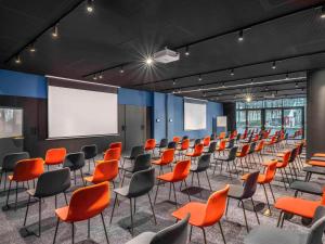 uma sala de conferências com cadeiras laranja e um ecrã de projecção em TRIBE Budapest Stadium em Budapeste