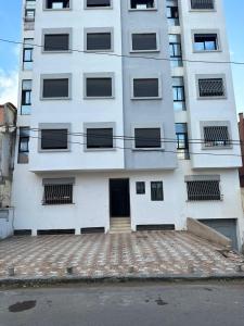 a tall white building with a door in front of it at Apprt Ennakhil 1 in El Jadida