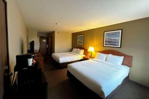 a hotel room with two beds and a television at Travelodge by Wyndham Rapid City - Black Hills in Rapid City