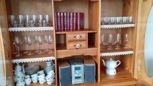 a wooden cabinet with wine glasses and a microwave at Komfort 4 Sterne Wohnung " Flut " für 4 Erw Kleinkind in Ostfriesland in Utarp