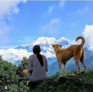una mujer sentada al lado de un perro en una montaña en Three daughters family home, en Pokhara
