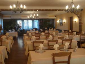 a dining room with white tables and chairs and chandeliers at Hôtel Restaurant Anglade in Le Nayrac