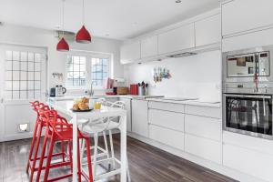 a white kitchen with white cabinets and red stools at Spacious 4 Bedroom House with Lovely Large Garden in Nottingham