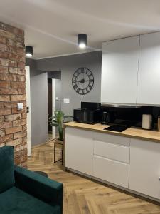 a kitchen with white cabinets and a clock on the wall at Apartament Rose Valley Dwa Zero in Szczytna