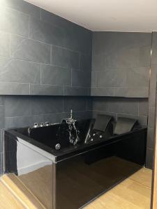 a black bath tub in a bathroom with black tiles at Casa Rural Hoyo del moro in Liétor